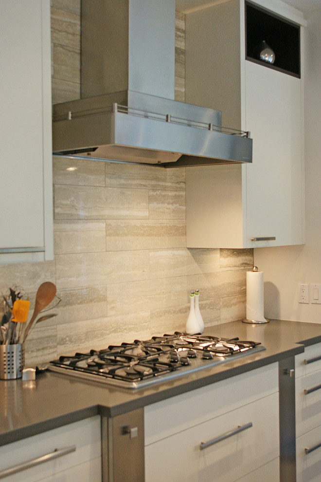 Example of a large minimalist galley eat-in kitchen design in Toronto with flat-panel cabinets, white cabinets, solid surface countertops, stainless steel appliances and an island