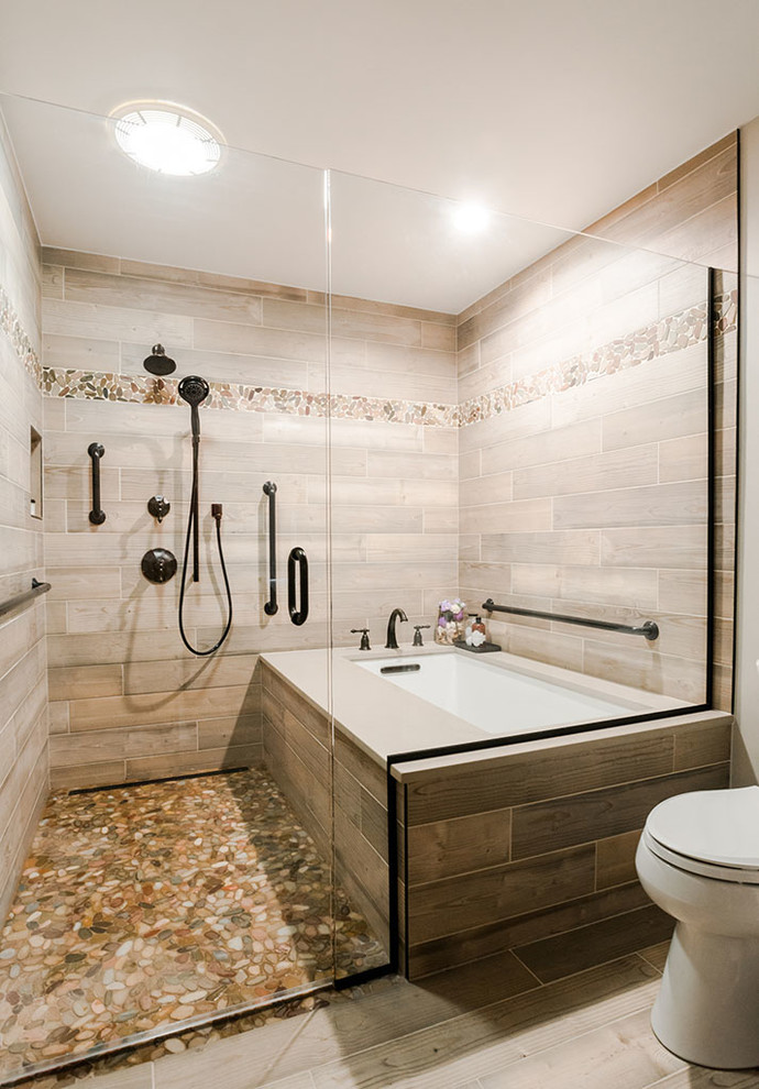 Mid-sized contemporary master bathroom in Baltimore with light wood cabinets, a corner tub, a shower/bathtub combo, a one-piece toilet, multi-coloured tile, porcelain tile, beige walls, porcelain floors, a drop-in sink, engineered quartz benchtops, multi-coloured floor and a hinged shower door.