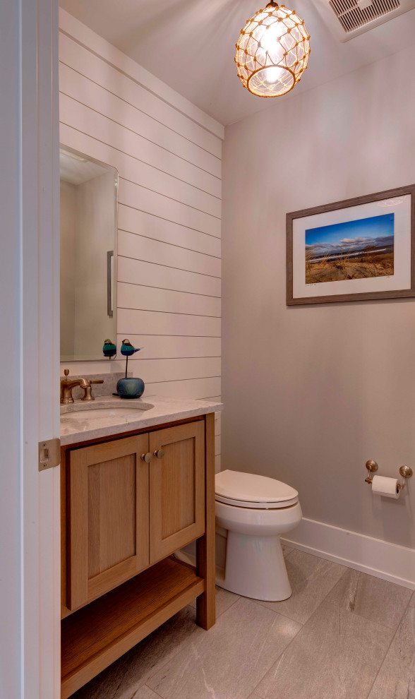 Example of a small classic porcelain tile and gray floor powder room design in Boston with recessed-panel cabinets, light wood cabinets, an undermount sink, quartzite countertops, gray countertops and a freestanding vanity