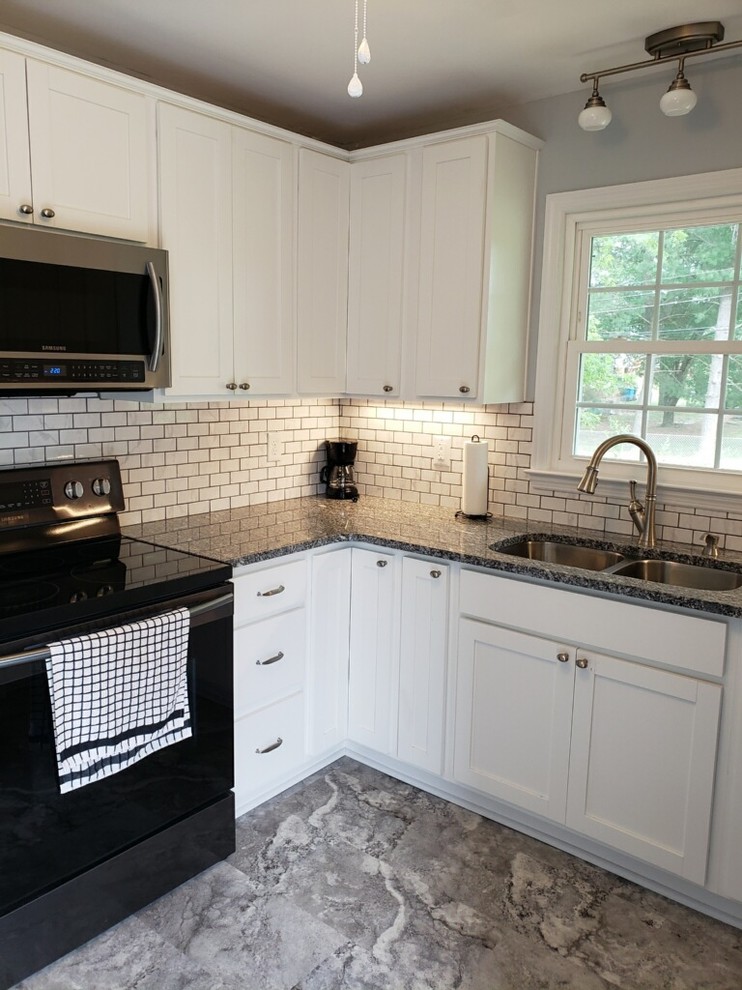 Example of a small mountain style u-shaped vinyl floor and gray floor enclosed kitchen design with an undermount sink, shaker cabinets, white cabinets, granite countertops, white backsplash, subway tile backsplash, black appliances, no island and multicolored countertops