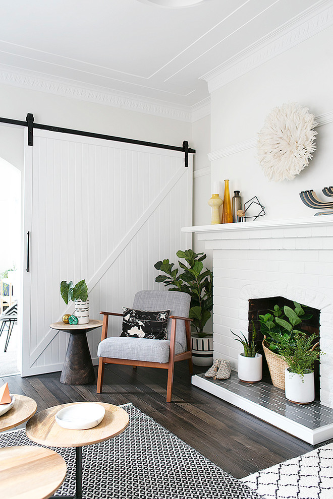 Photo of a large eclectic enclosed living room in Sydney with white walls, dark hardwood floors, a standard fireplace, a brick fireplace surround, no tv and grey floor.