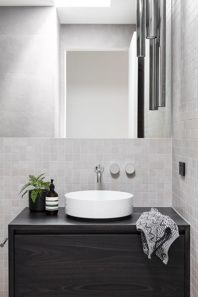Photo of a contemporary bathroom in Melbourne with dark wood cabinets, gray tile, mosaic tile, grey walls, ceramic floors, a vessel sink, wood benchtops and grey floor.