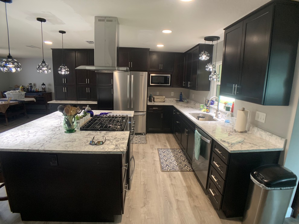 Photo of a mid-sized arts and crafts l-shaped eat-in kitchen in Orlando with an undermount sink, shaker cabinets, dark wood cabinets, quartz benchtops, stainless steel appliances, vinyl floors, with island, beige floor and multi-coloured benchtop.