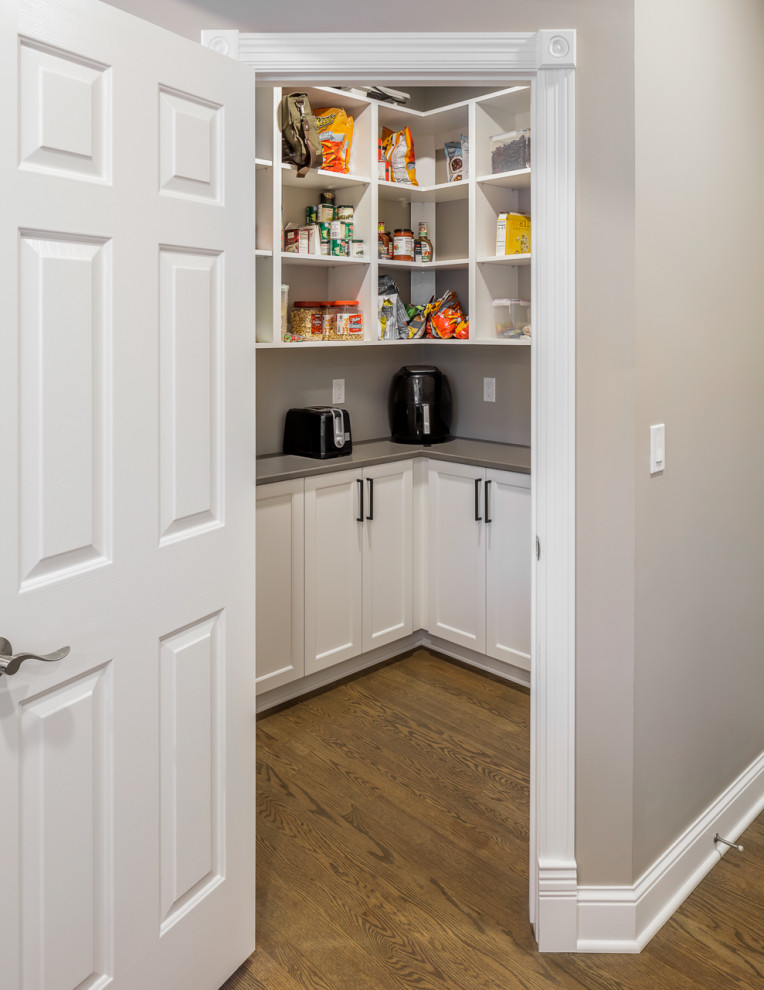 Example of a brown floor kitchen pantry design with shaker cabinets, white cabinets and gray backsplash