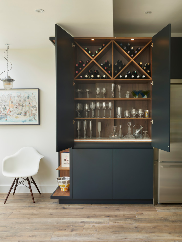 Large contemporary l-shaped eat-in kitchen in London with an integrated sink, blue cabinets, marble benchtops, metallic splashback, mirror splashback, light hardwood floors, with island, brown floor and white benchtop.