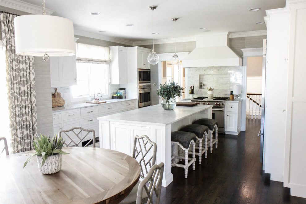Inspiration for a large transitional l-shaped eat-in kitchen in Chicago with an undermount sink, flat-panel cabinets, white cabinets, marble benchtops, dark hardwood floors, with island, white splashback, stone tile splashback, stainless steel appliances and brown floor.