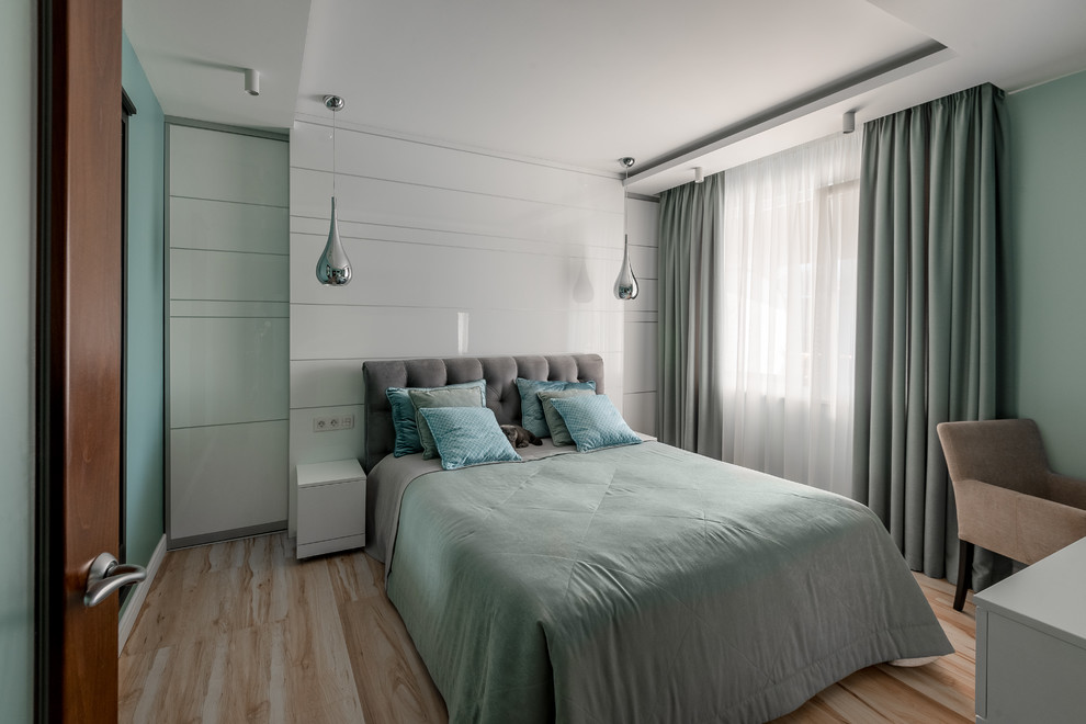 This is an example of a contemporary master bedroom in Other with green walls and light hardwood floors.