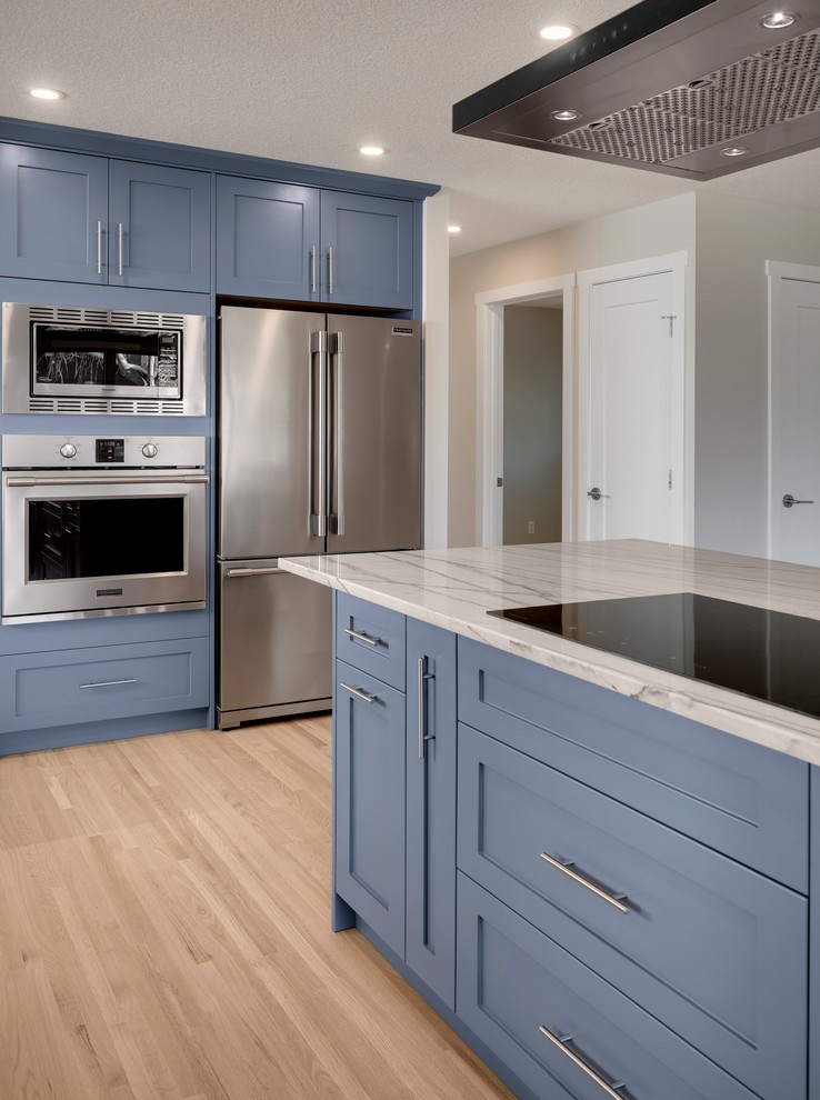 Design ideas for a transitional l-shaped kitchen in Calgary with an undermount sink, shaker cabinets, grey cabinets, quartzite benchtops, white splashback, cement tile splashback, stainless steel appliances, light hardwood floors and white benchtop.