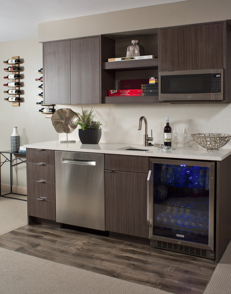 Photo of a contemporary single-wall wet bar in Denver with an undermount sink, flat-panel cabinets, dark wood cabinets, white splashback, carpet, grey floor and white benchtop.