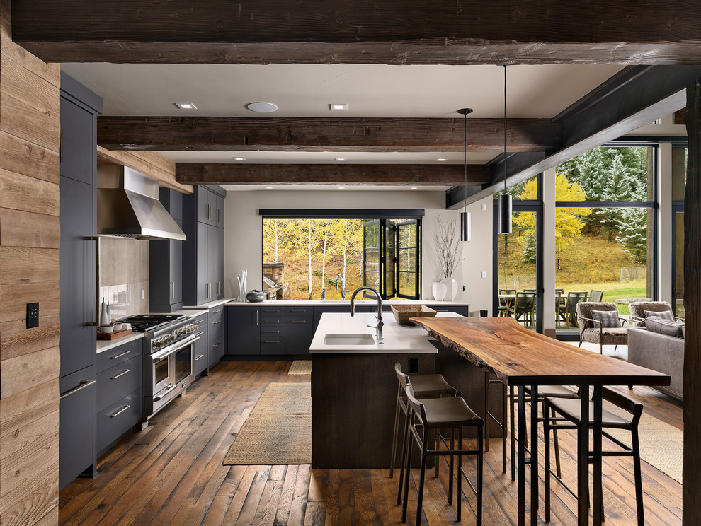 Inspiration for a large country l-shaped eat-in kitchen in Denver with an undermount sink, flat-panel cabinets, grey cabinets, grey splashback, panelled appliances, medium hardwood floors, with island, brown floor and white benchtop.