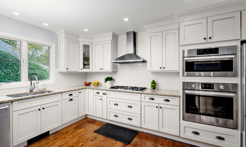 Inspiration for a mid-sized transitional l-shaped dark wood floor and brown floor kitchen remodel in Bridgeport with an undermount sink, recessed-panel cabinets, white cabinets, granite countertops, white backsplash, subway tile backsplash, stainless steel appliances and no island