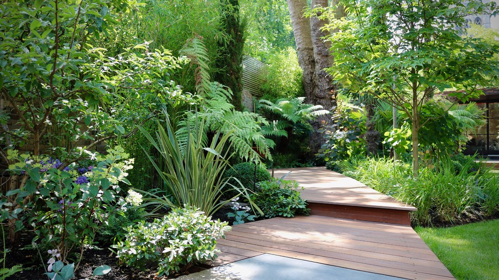 Photo of a large tropical backyard partial sun formal garden in London with decking and a garden path.