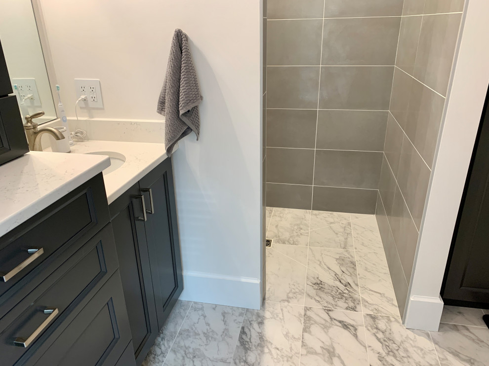 Klassisk inredning av ett mellanstort vit vitt en-suite badrum, med släta luckor, grå skåp, en kantlös dusch, grå kakel, porslinskakel, grå väggar, klinkergolv i porslin, ett undermonterad handfat, bänkskiva i kvarts, grått golv och med dusch som är öppen