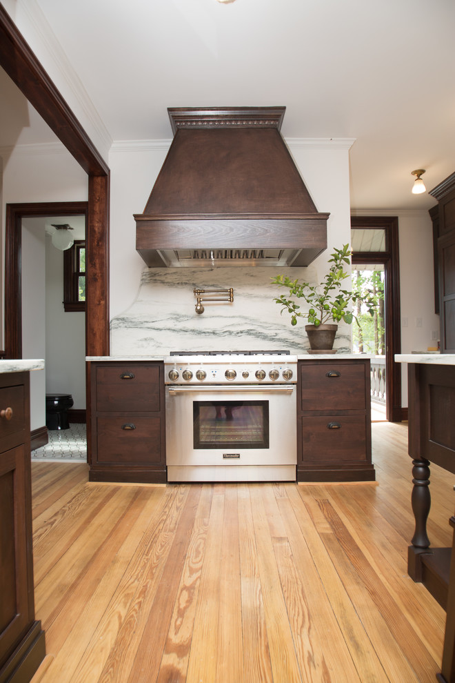 Photo of an expansive traditional galley kitchen pantry in St Louis with flat-panel cabinets, dark wood cabinets, marble benchtops, white splashback, marble splashback, panelled appliances, medium hardwood floors, with island and white benchtop.