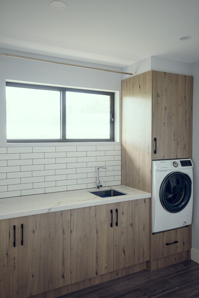 Inspiration for a contemporary galley utility room in Melbourne with an undermount sink, flat-panel cabinets, light wood cabinets, quartz benchtops, white walls, dark hardwood floors and white benchtop.