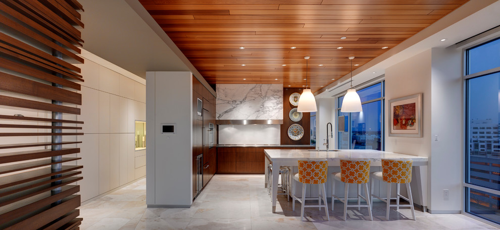 Mid-sized contemporary l-shaped eat-in kitchen in Indianapolis with a single-bowl sink, flat-panel cabinets, medium wood cabinets, marble benchtops, white splashback, glass sheet splashback, panelled appliances, travertine floors and with island.