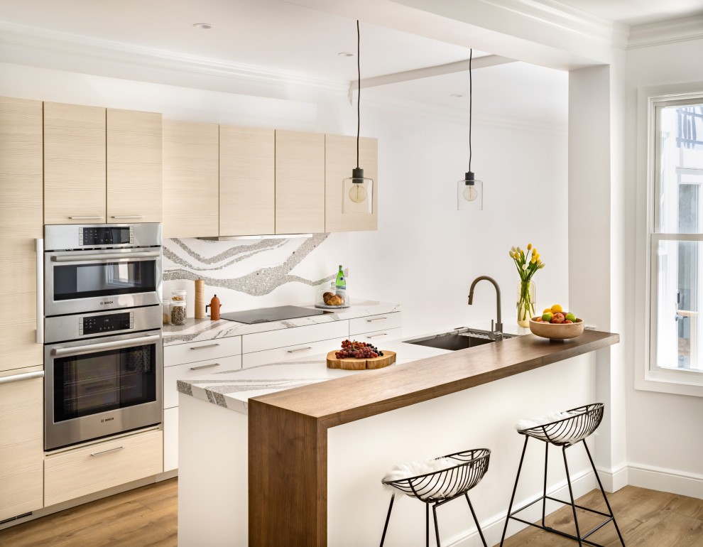 This is an example of a contemporary kitchen in San Francisco with an undermount sink, flat-panel cabinets, light wood cabinets, quartz benchtops, multi-coloured splashback, engineered quartz splashback, stainless steel appliances, with island and multi-coloured benchtop.