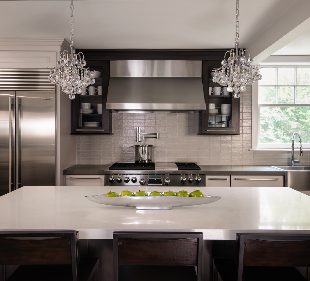Photo of a mid-sized contemporary l-shaped eat-in kitchen in Birmingham with grey splashback, glass tile splashback, stainless steel appliances, dark hardwood floors, with island, quartz benchtops, flat-panel cabinets, dark wood cabinets, white benchtop, brown floor and a farmhouse sink.