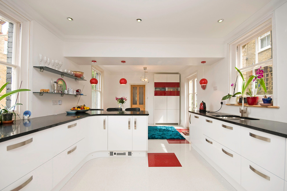 This is an example of a contemporary u-shaped eat-in kitchen in Kent with an undermount sink, white cabinets, red splashback, glass sheet splashback, stainless steel appliances and flat-panel cabinets.
