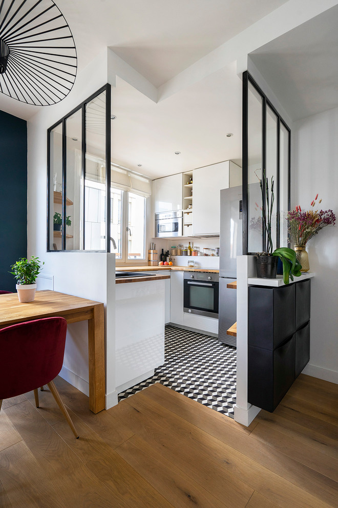 Inspiration for a small contemporary u-shaped separate kitchen in Paris with a single-bowl sink, white cabinets, wood benchtops, white splashback, stainless steel appliances, ceramic floors, no island, brown benchtop, flat-panel cabinets and multi-coloured floor.