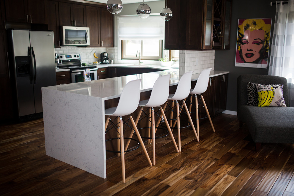 Inspiration for a mid-sized transitional u-shaped enclosed kitchen remodel in Omaha with shaker cabinets, dark wood cabinets, quartz countertops, white backsplash, subway tile backsplash, stainless steel appliances and a peninsula