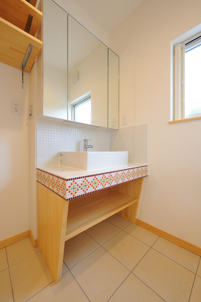 他の地域にあるおしゃれなトイレ・洗面所 (オープンシェルフ、淡色木目調キャビネット、白いタイル、白い壁、タイルの洗面台、ベージュの床、白い洗面カウンター) の写真