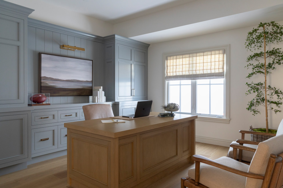 Example of a beach style built-in desk medium tone wood floor and brown floor home office design in Orange County with blue walls