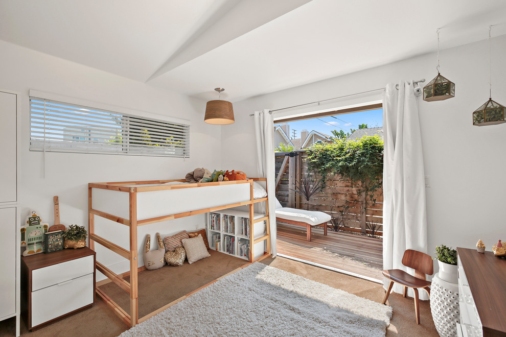 This is an example of a midcentury gender-neutral kids' bedroom for kids 4-10 years old in Orange County with white walls, carpet and brown floor.