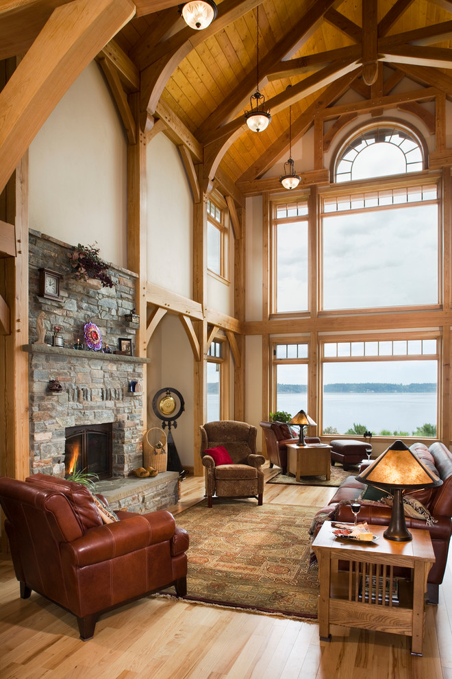 Large mountain style open concept medium tone wood floor living room photo in Seattle with beige walls, a standard fireplace, a stone fireplace and no tv