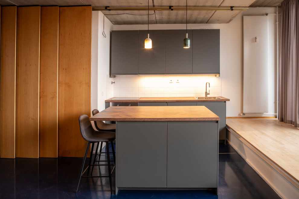 Offene, Zweizeilige, Mittelgroße Moderne Küche mit Einbauwaschbecken, flächenbündigen Schrankfronten, grauen Schränken, Arbeitsplatte aus Holz, Küchenrückwand in Weiß, Rückwand aus Keramikfliesen, Küchengeräten aus Edelstahl, Kücheninsel, blauem Boden und brauner Arbeitsplatte in Berlin