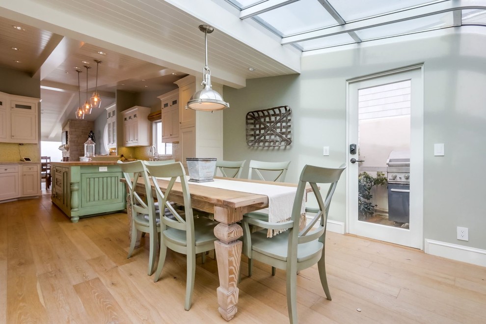 This is an example of a mid-sized beach style u-shaped eat-in kitchen in Orange County with a farmhouse sink, recessed-panel cabinets, white cabinets, mosaic tile splashback, panelled appliances, medium hardwood floors, with island and brown floor.