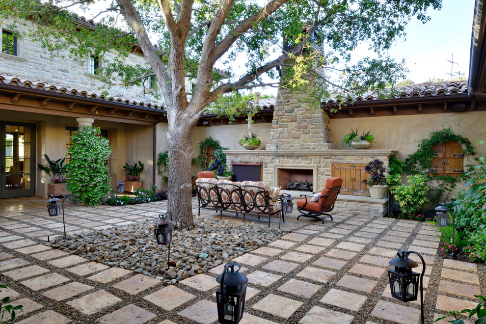 Photo of an expansive mediterranean backyard patio in San Diego with no cover, natural stone pavers and with fireplace.