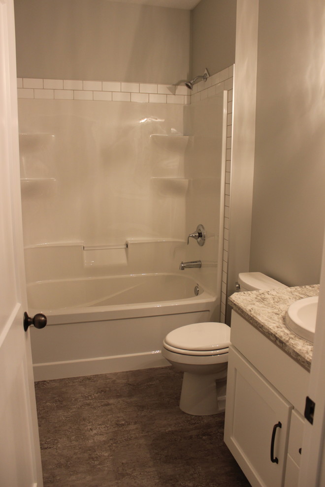 This is an example of a mid-sized traditional master bathroom in Edmonton with recessed-panel cabinets, white cabinets, a drop-in tub, a shower/bathtub combo, a two-piece toilet, white tile, ceramic tile, beige walls, vinyl floors, a drop-in sink, laminate benchtops, multi-coloured floor and a shower curtain.