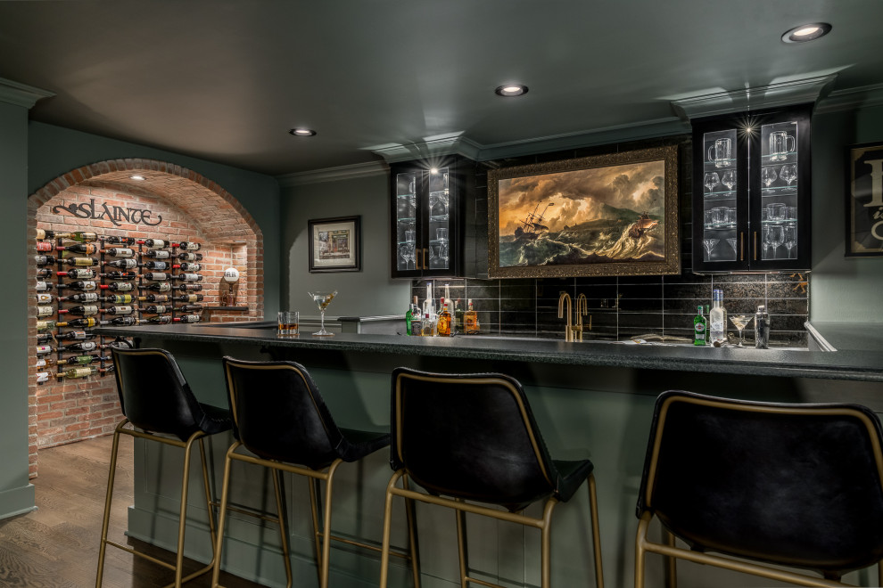 Design ideas for a large transitional single-wall seated home bar in New York with an undermount sink, glass-front cabinets, black cabinets, soapstone benchtops, black splashback, glass tile splashback, dark hardwood floors, brown floor and black benchtop.