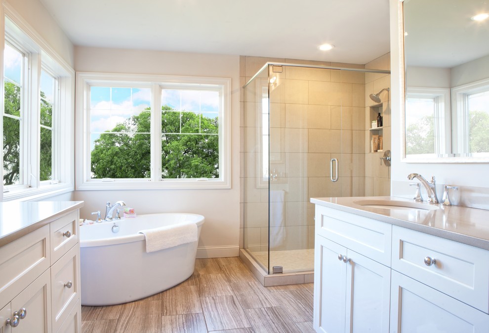 This is an example of a mid-sized traditional master bathroom in Minneapolis with recessed-panel cabinets, white cabinets, a freestanding tub, brown tile, porcelain tile, white walls, ceramic floors, an undermount sink and granite benchtops.