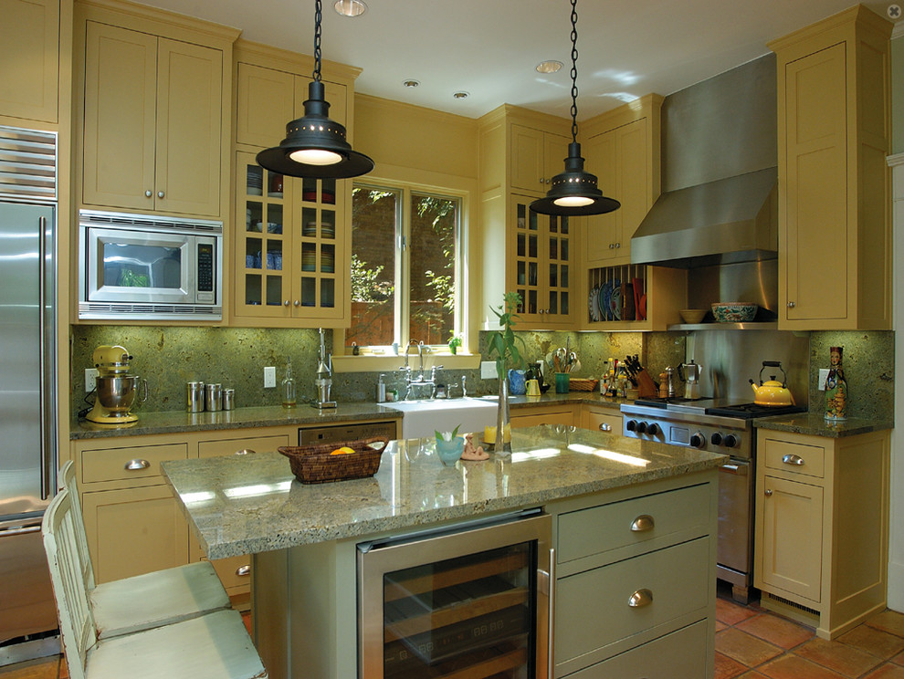 Photo of a mid-sized modern l-shaped eat-in kitchen in Dallas with a drop-in sink, recessed-panel cabinets, yellow cabinets, quartzite benchtops, green splashback, ceramic splashback, stainless steel appliances, terra-cotta floors and with island.