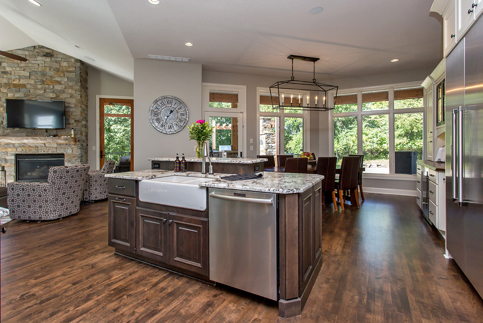 Example of a huge transitional medium tone wood floor kitchen design with an undermount sink, flat-panel cabinets, granite countertops, white backsplash, ceramic backsplash, stainless steel appliances and two islands