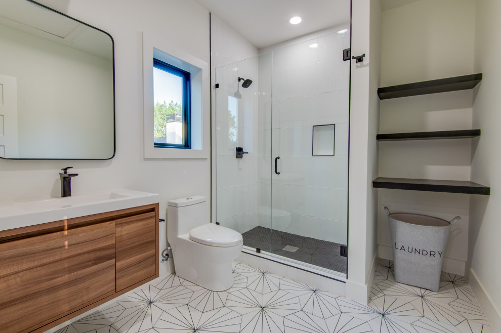 This is an example of a mid-sized modern kids bathroom in Dallas with medium wood cabinets, a corner tub, a one-piece toilet, white tile, slate, white walls, marble floors, a drop-in sink, solid surface benchtops, multi-coloured floor, a hinged shower door, white benchtops, a niche, a single vanity and a floating vanity.