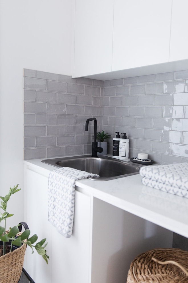 Mid-sized modern dedicated laundry room in Canberra - Queanbeyan with a drop-in sink, quartz benchtops, white walls, porcelain floors, a side-by-side washer and dryer and grey floor.