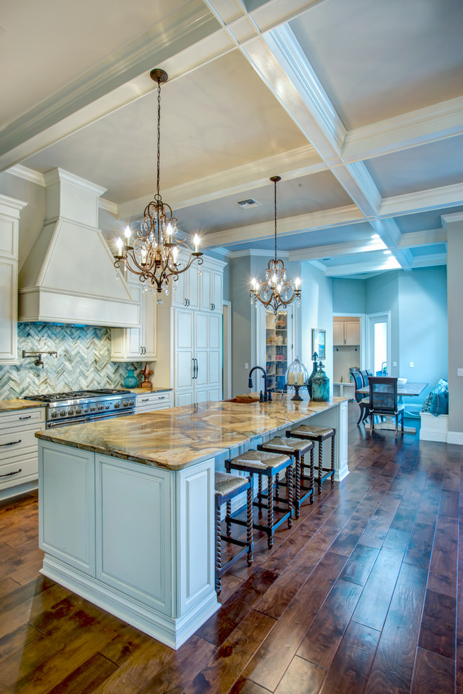 Example of a large transitional l-shaped dark wood floor and brown floor open concept kitchen design in Orlando with a farmhouse sink, raised-panel cabinets, white cabinets, granite countertops, blue backsplash, stone tile backsplash, paneled appliances and an island