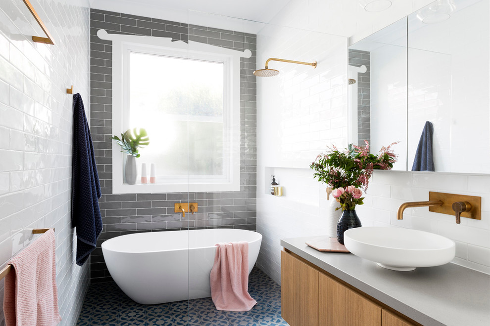 Photo of a large contemporary master bathroom in Melbourne with flat-panel cabinets, medium wood cabinets, a freestanding tub, an alcove shower, a two-piece toilet, ceramic tile, grey walls, ceramic floors, a vessel sink, concrete benchtops, blue floor, a hinged shower door and grey benchtops.