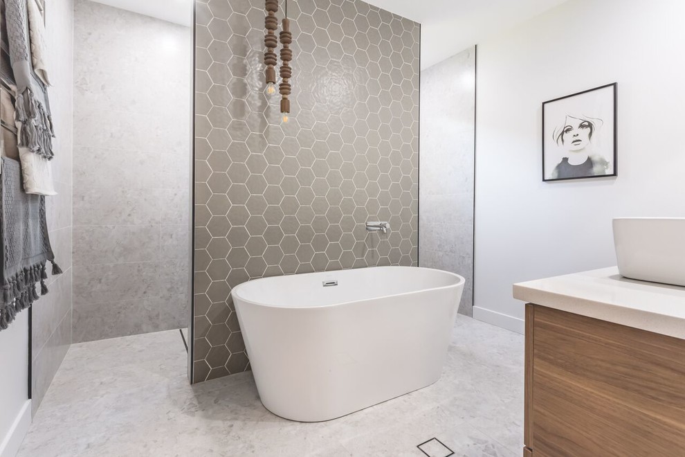 Inspiration for a large contemporary master bathroom in Newcastle - Maitland with recessed-panel cabinets, medium wood cabinets, a freestanding tub, an open shower, a two-piece toilet, gray tile, mosaic tile, grey walls, terrazzo floors, a wall-mount sink, engineered quartz benchtops, white floor and an open shower.