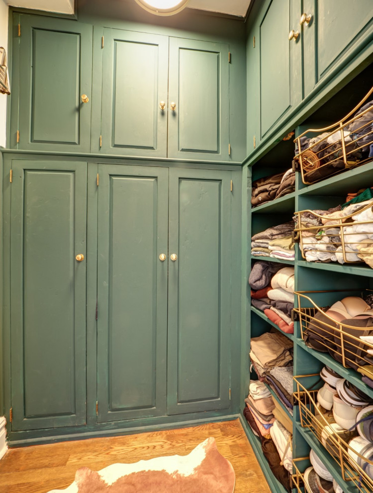 Inspiration for a mid-sized traditional gender-neutral storage and wardrobe in New York with raised-panel cabinets, green cabinets, medium hardwood floors and brown floor.