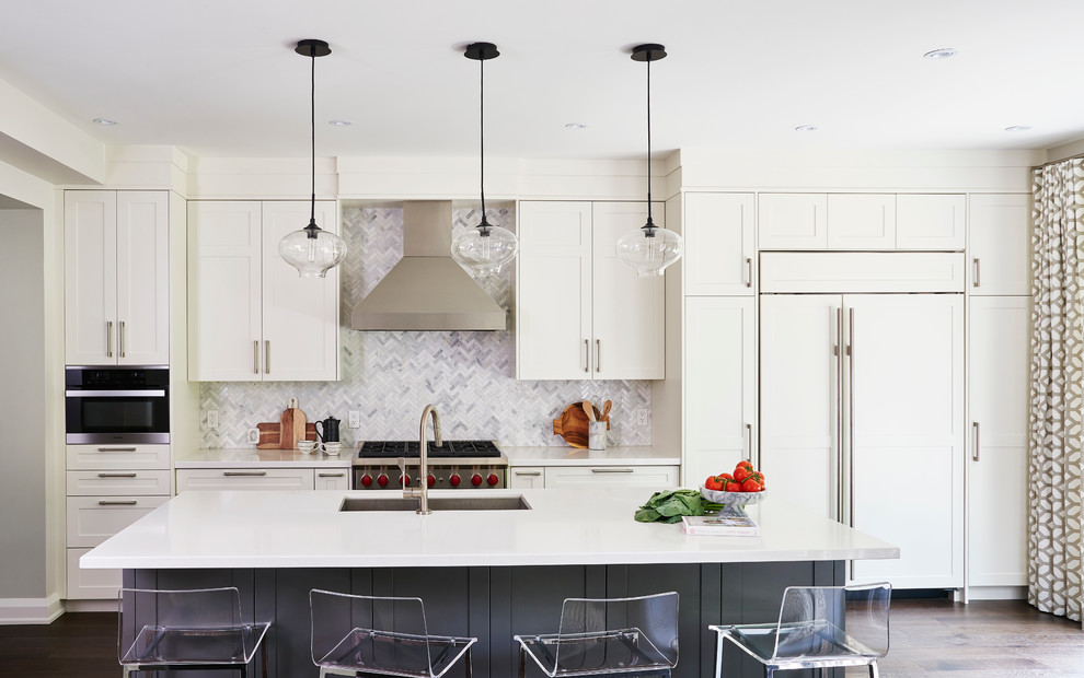 This is an example of a mid-sized transitional single-wall open plan kitchen in Toronto with an undermount sink, shaker cabinets, white cabinets, quartz benchtops, white splashback, stone tile splashback, stainless steel appliances, medium hardwood floors and with island.
