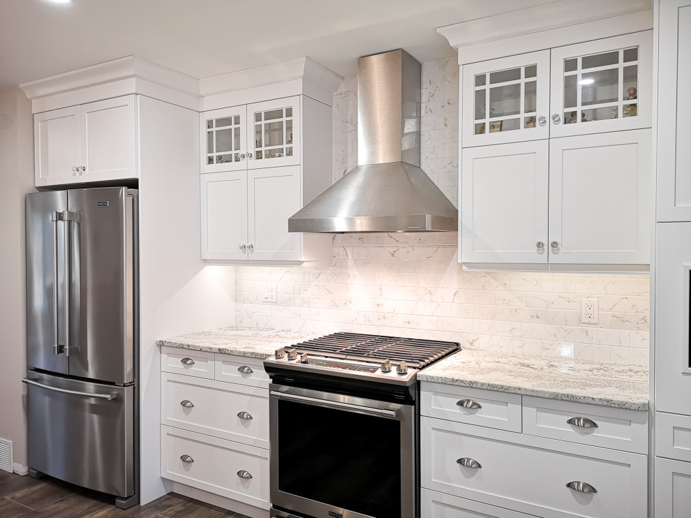 Mid-sized country single-wall eat-in kitchen in Toronto with an undermount sink, shaker cabinets, white cabinets, quartz benchtops, white splashback, ceramic splashback, stainless steel appliances, vinyl floors, with island, brown floor and multi-coloured benchtop.