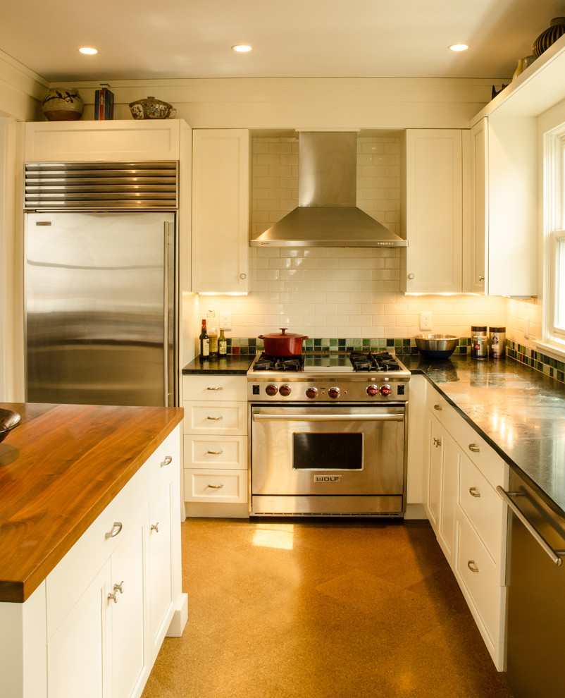 Example of a large transitional l-shaped cork floor and brown floor eat-in kitchen design in Boston with an undermount sink, shaker cabinets, white cabinets, soapstone countertops, green backsplash, ceramic backsplash, stainless steel appliances and an island