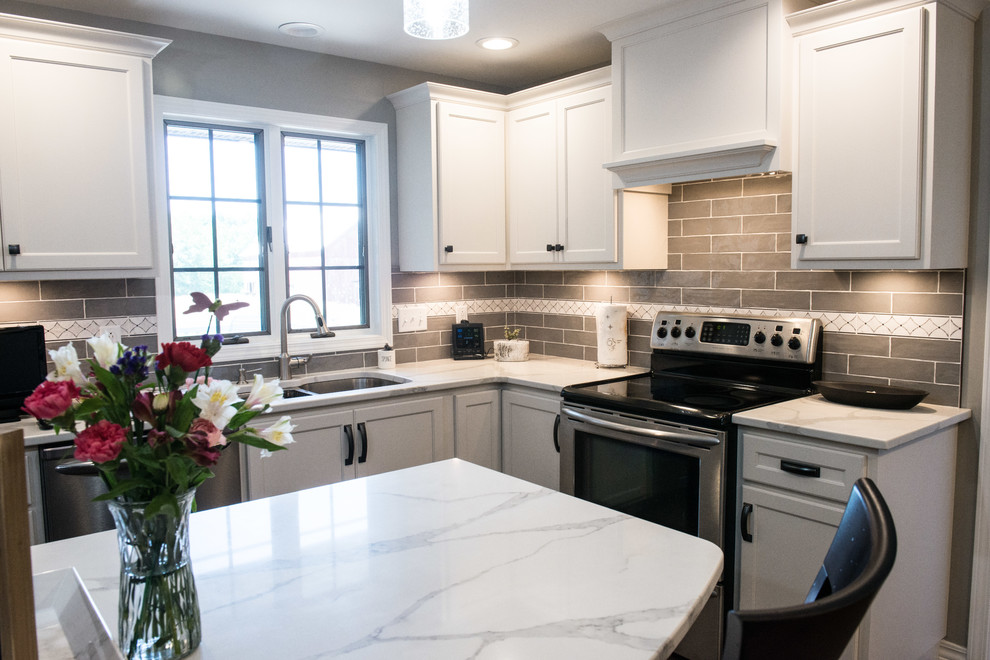 Large transitional u-shaped laminate floor and brown floor eat-in kitchen photo with a double-bowl sink, shaker cabinets, white cabinets, quartz countertops, gray backsplash, subway tile backsplash, stainless steel appliances, an island and white countertops