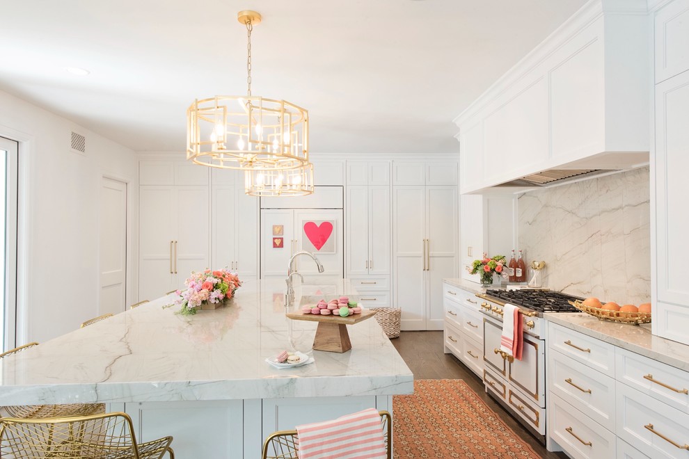 Example of a large transitional l-shaped medium tone wood floor and brown floor open concept kitchen design with a farmhouse sink, recessed-panel cabinets, white cabinets, quartzite countertops, white backsplash, stone slab backsplash, paneled appliances and an island
