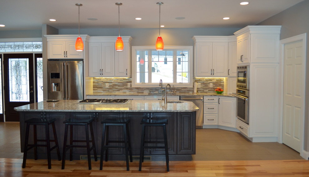Transitional l-shaped porcelain tile kitchen photo in Boston with an undermount sink, raised-panel cabinets, white cabinets, quartz countertops, multicolored backsplash, mosaic tile backsplash, stainless steel appliances and an island