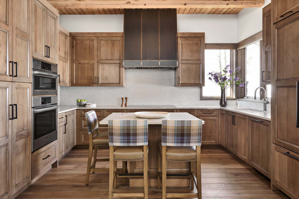 Inspiration for a transitional u-shaped medium tone wood floor, brown floor and wood ceiling kitchen remodel in Denver with an undermount sink, recessed-panel cabinets, medium tone wood cabinets, gray backsplash, paneled appliances, an island and white countertops